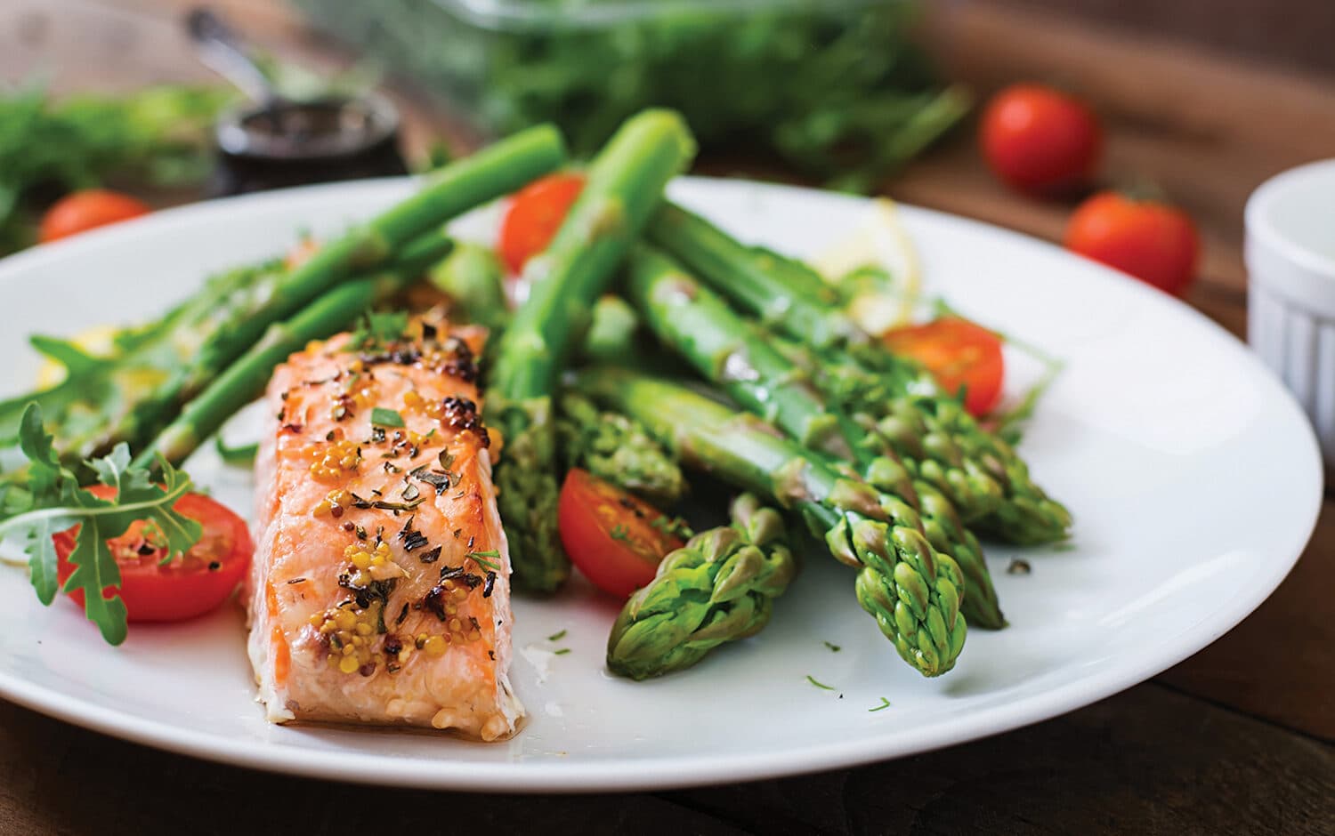 Baked salmon garnished with asparagus and tomatoes with herbs.